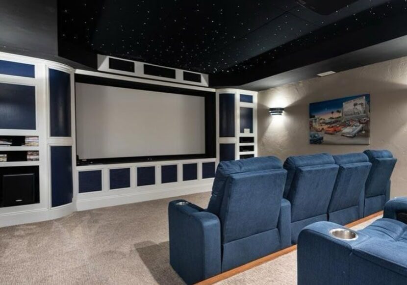 AV installation services for a custom home theater with projector screen and blue seating
