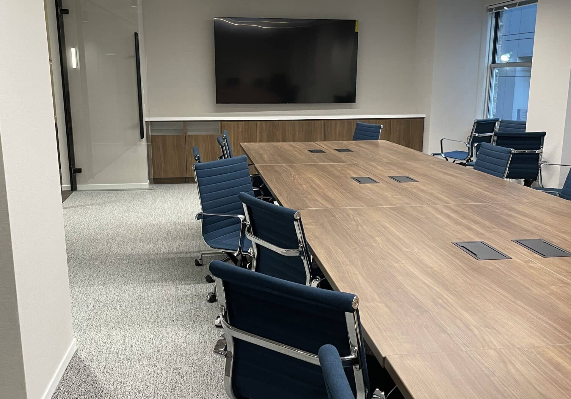 Conference room AV installation with wall-mounted display and executive boardroom table